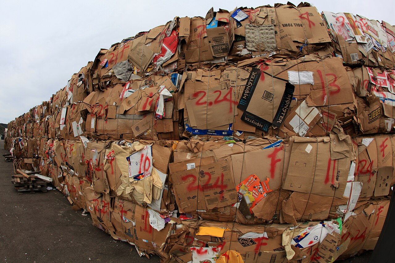 A wall of baled cardboard stacked at a recycling yard, ready to be sold back into paper making
