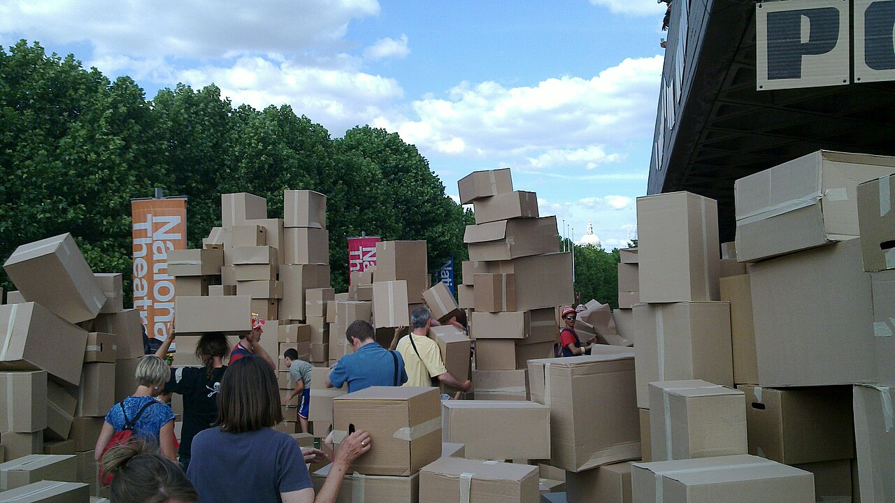 A mountain of empty cardboard boxes towering over people during a house-move event